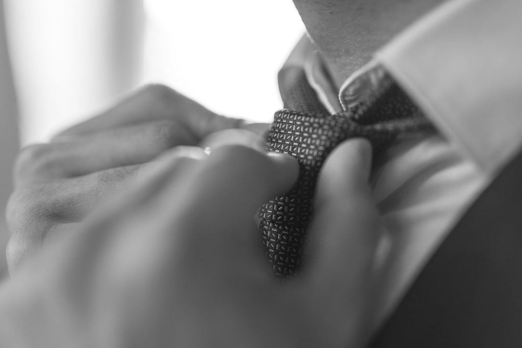 le marié ajuste son noeud de cravate du marié pendant la préparation mariage